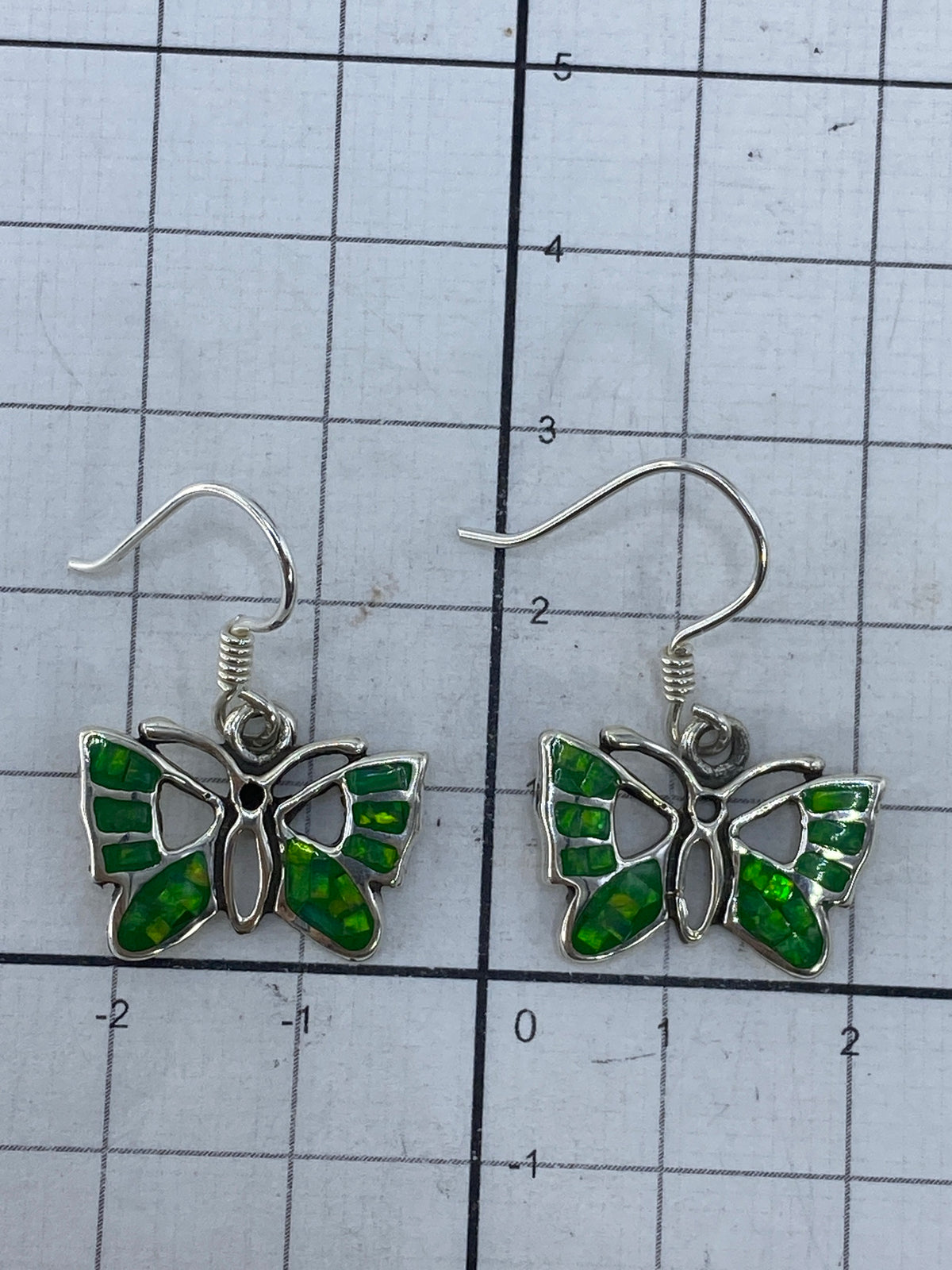 Aretes de mariposa ópalo verde sobre fondo blanco mostrando el Quinto 950