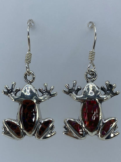 Aretes de rana en plata 950 sobre fondo gris, mostrando los destellos del ópalo