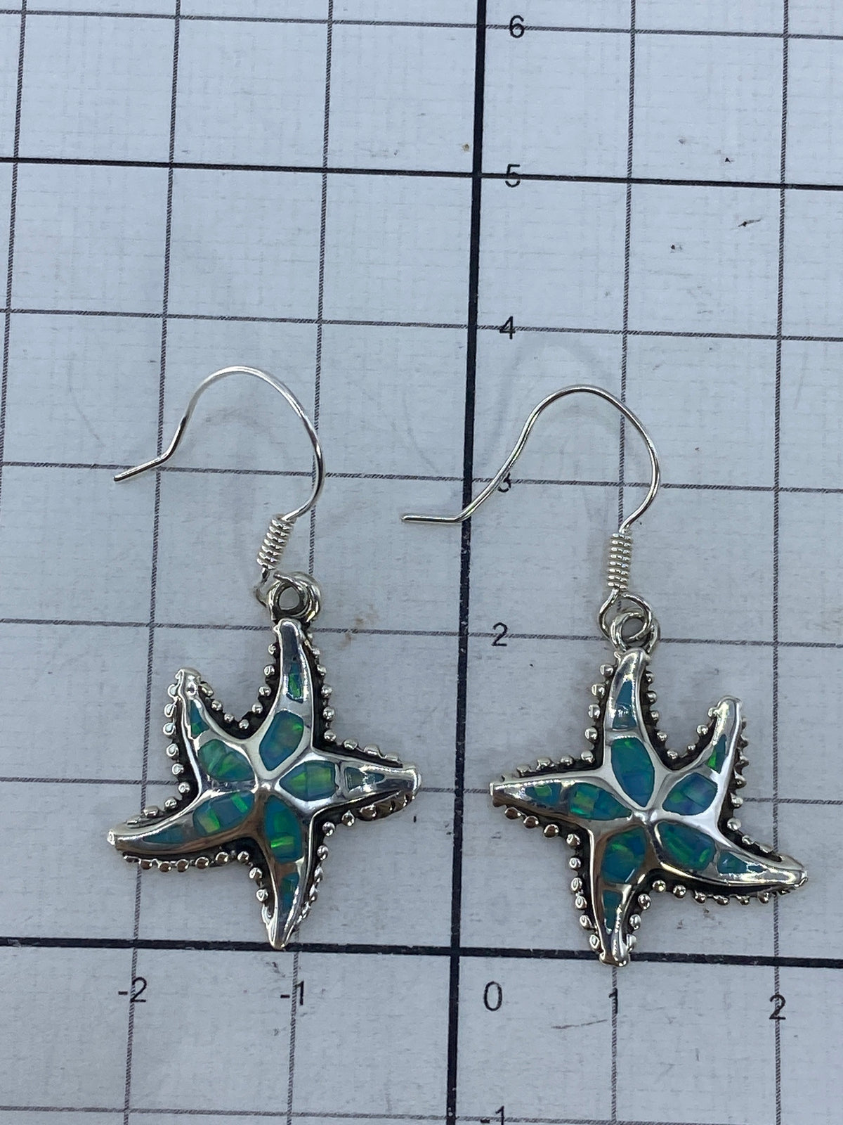 Aretes sobre medidor de centímetros mostrando el largo de 3.7 cm