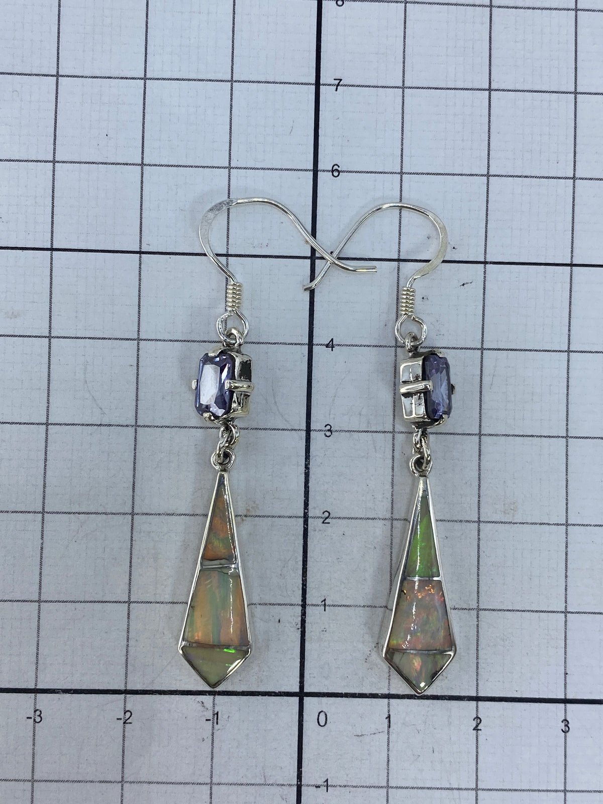 Aretes sobre regla de centímetros mostrando largo de 5.7 cm, con hallmark 950 visible