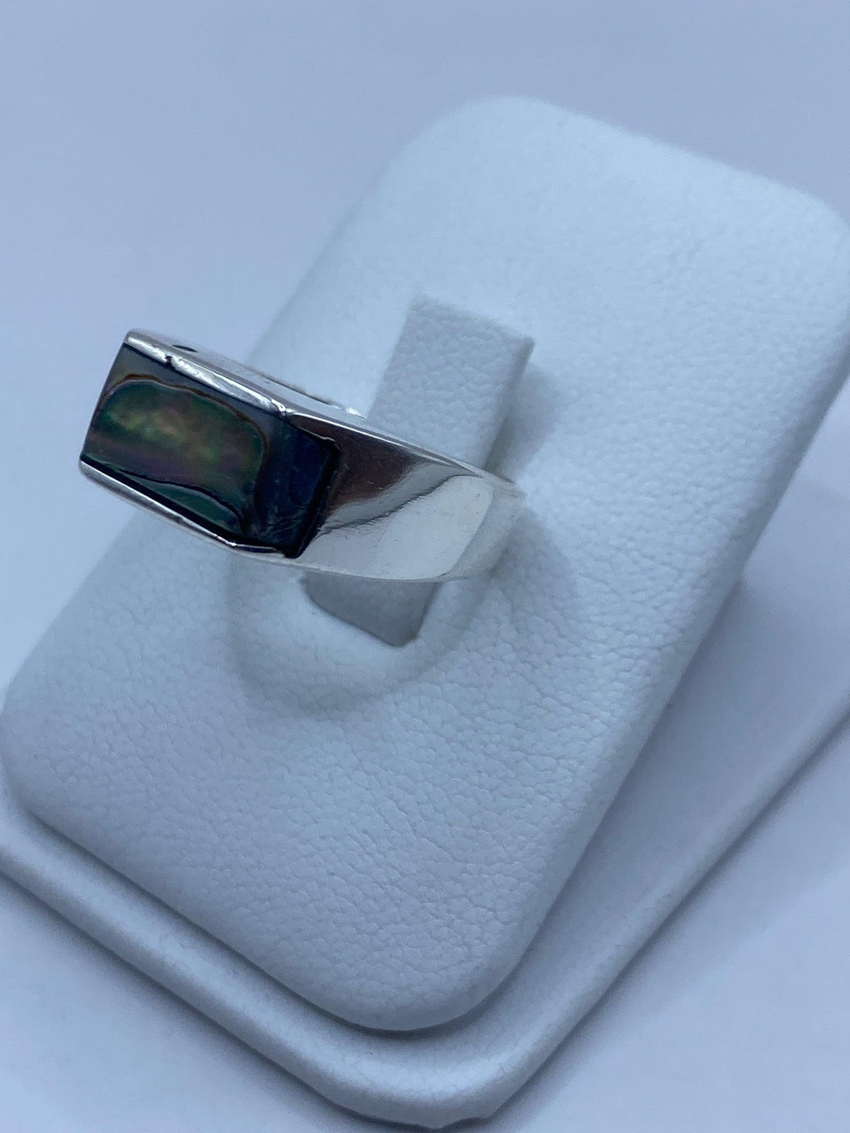Detalle frontal del anillo mostrando los destellos púrpura, verde y azul de la concha engastada