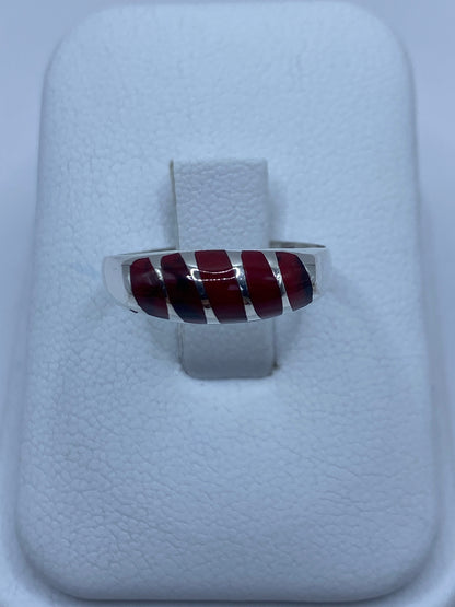 Anillo de plata 950 con coral rojo engastado en la mano de una persona