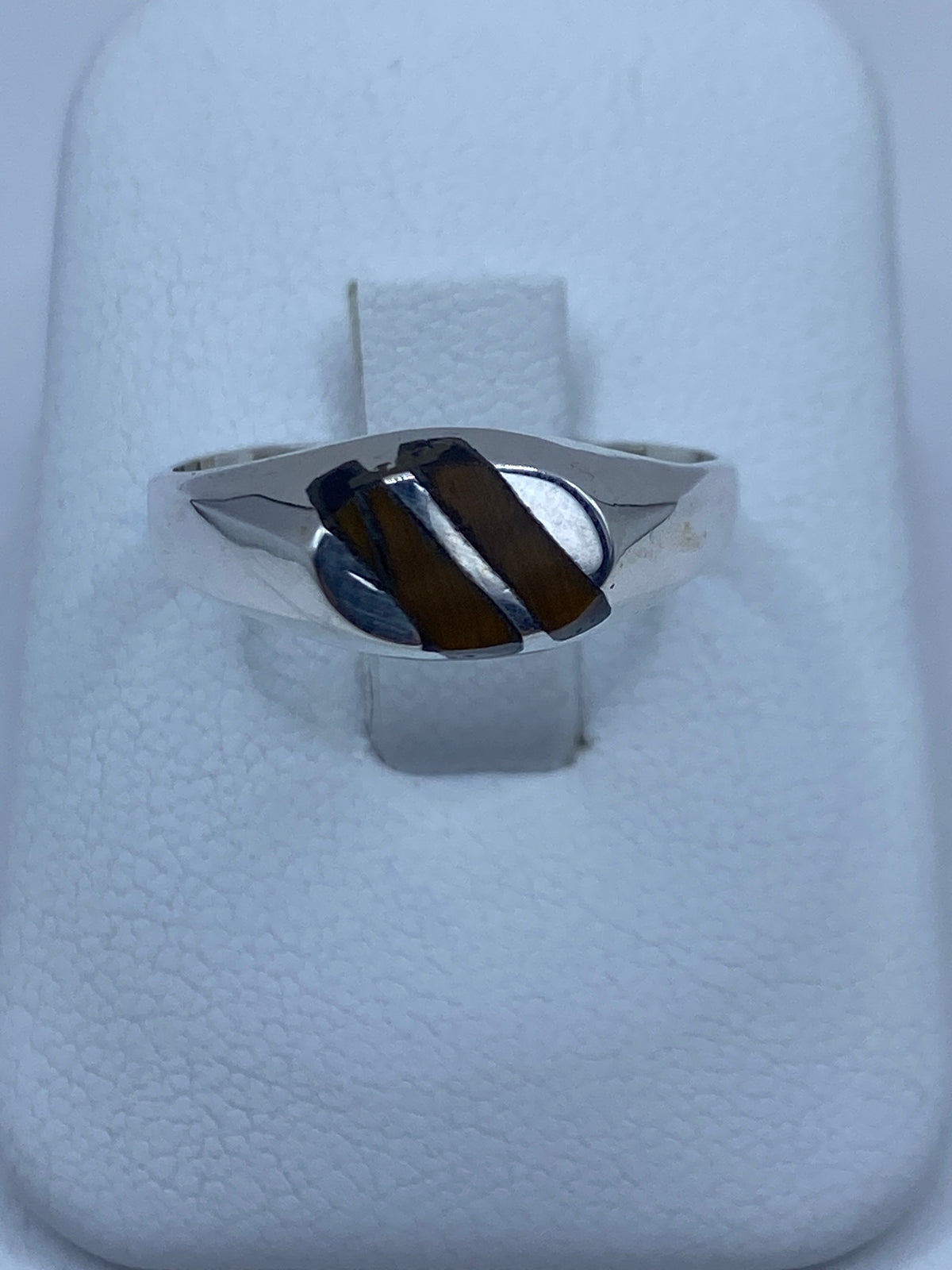 Anillo de plata 925 con piedra cafe engastada, visto de frente sobre anillo blanco