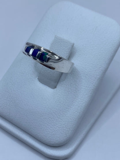 Anillo de plata con piedra azul puesto en el dedo, mostrando el engaste a mano