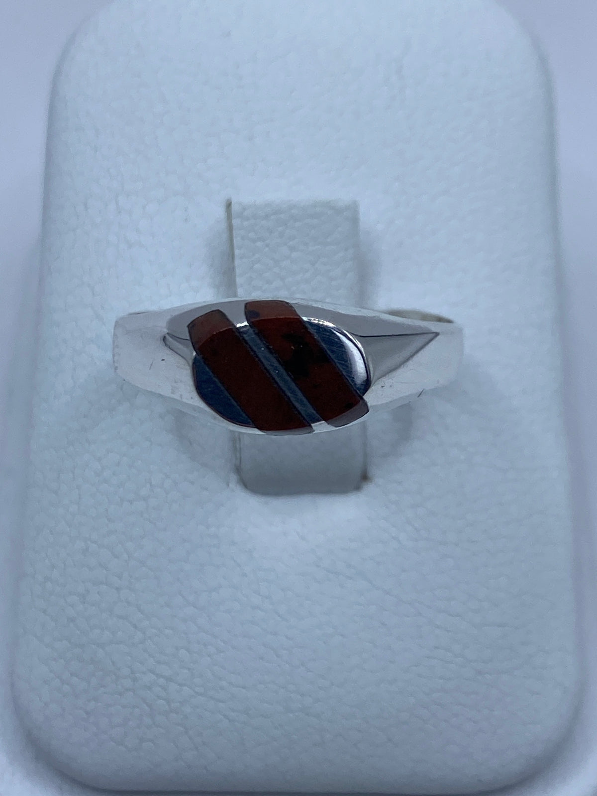 Anillo de plata con ojo de tigre café reposando en estuche blanco de presentación