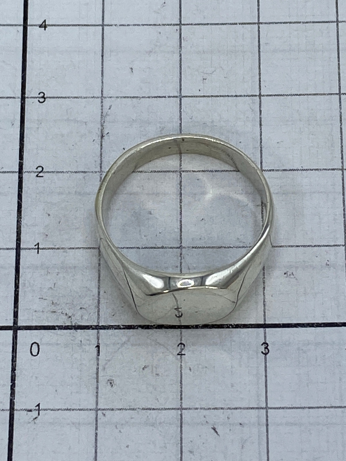 Anillo de plata cartoneado en escala de medida mostrando tamaño real