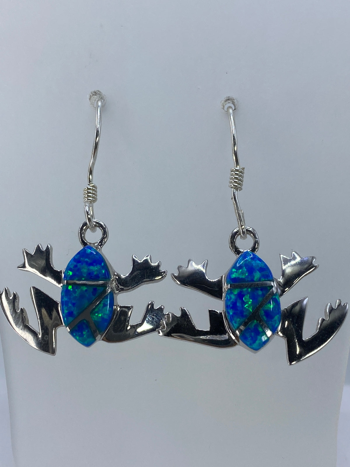 Aretes en la mano mostrando el color verde olivo del ópalo