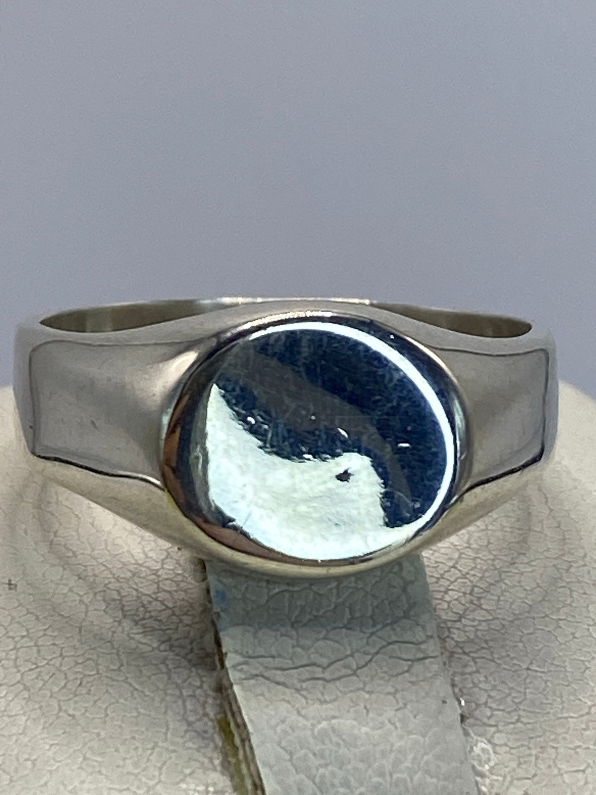 Anillo sello de plata sobre fondo gris, vista superior