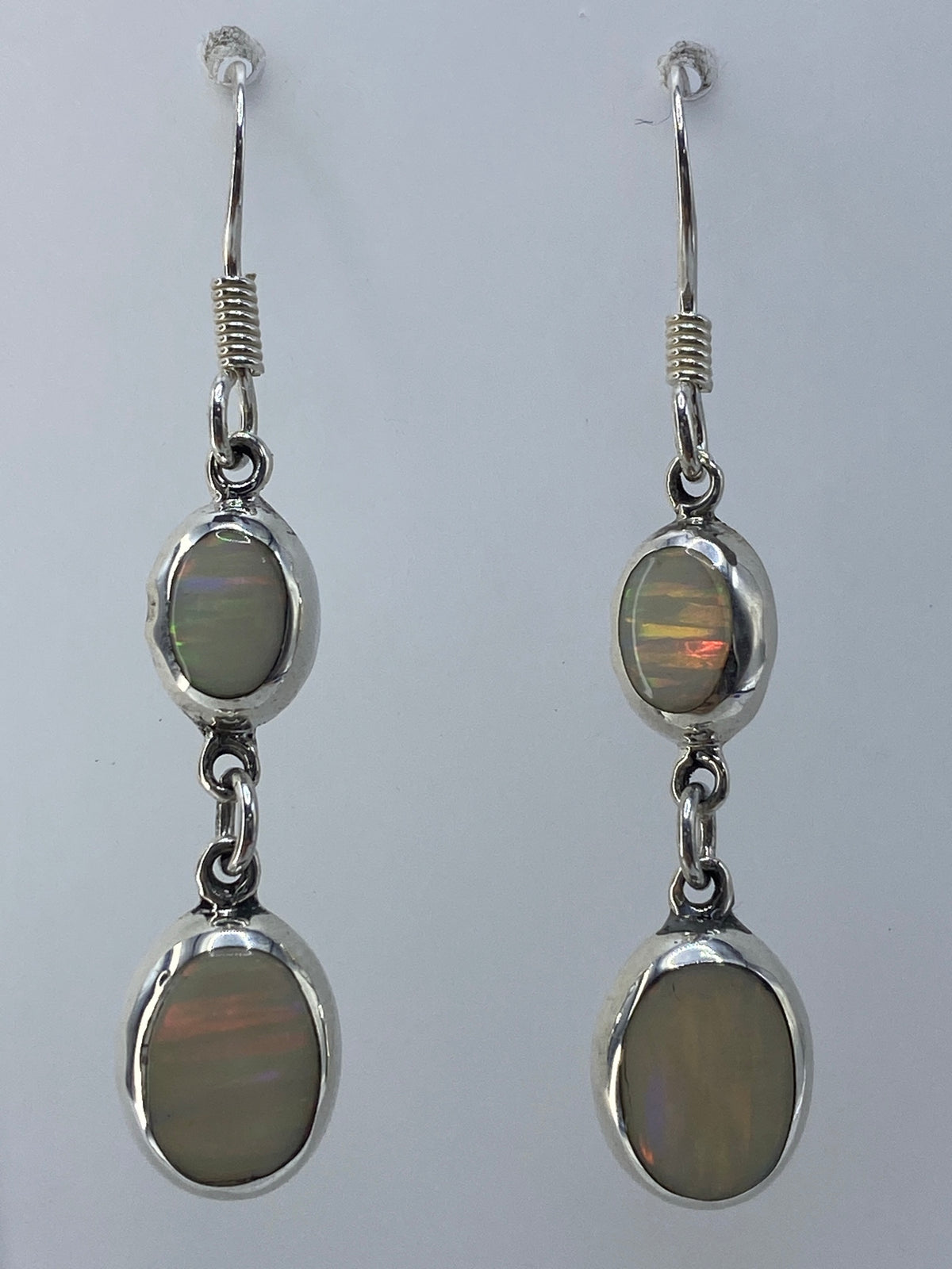 Par de aretes de plata con ópalo de fuego multicolor que refleja tonos verdes, dorados y rojos