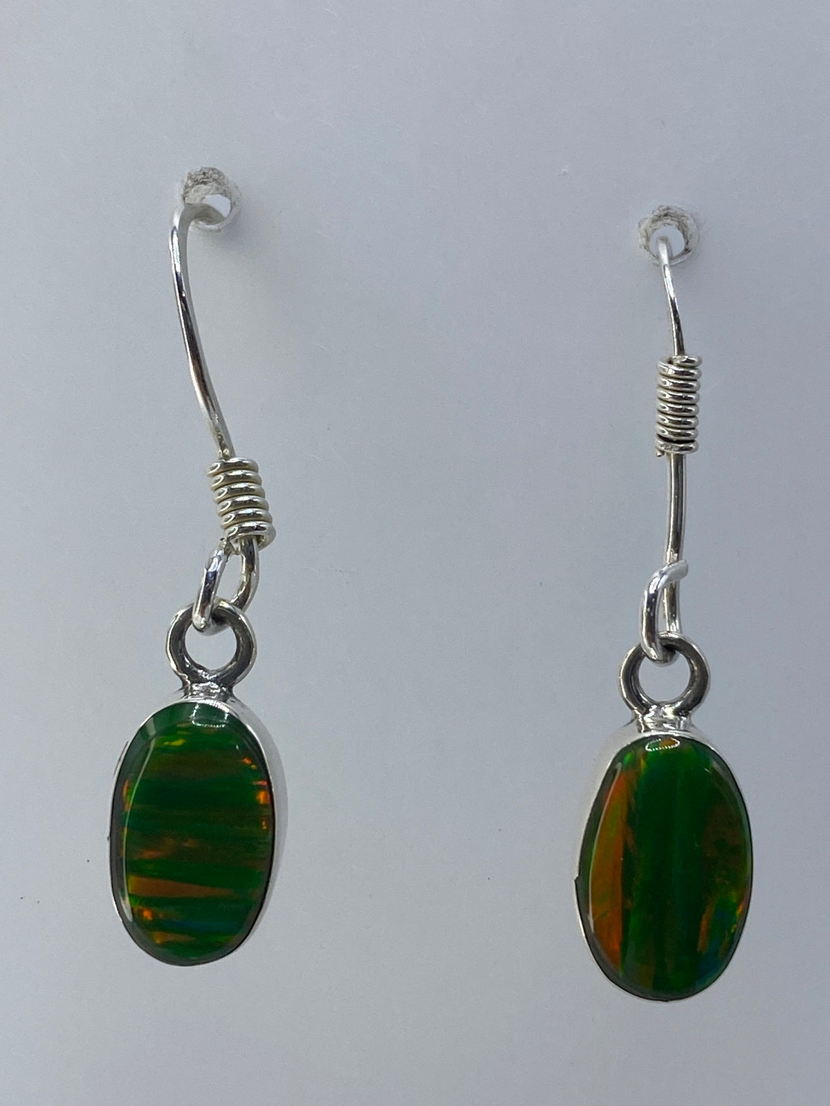 Detalle de la incrustación de piedra verde con reflejos ámbar en los aretes