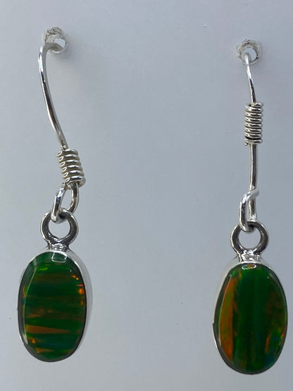 Aretes sobre paño gris claro mostrando el color verde profundo del ópalo