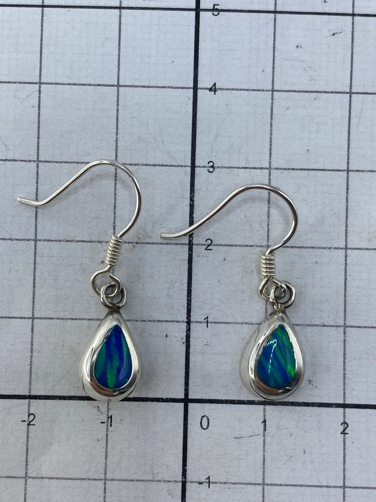 Aretes colgando mostrando el color verde olivo profundo del ópalo de fuego