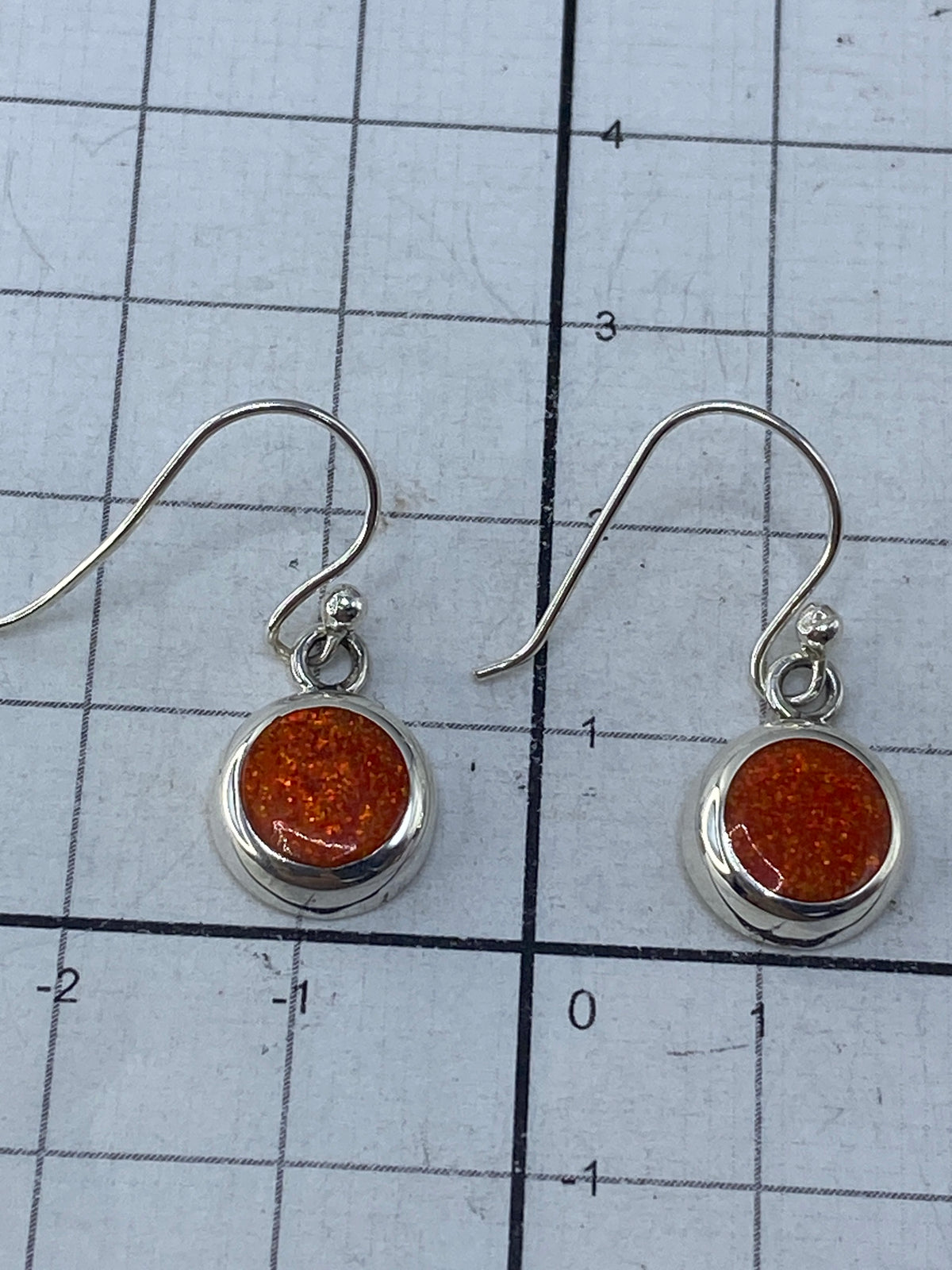 Aretes sobre regla métrica mostrando largo de 2.5 cm