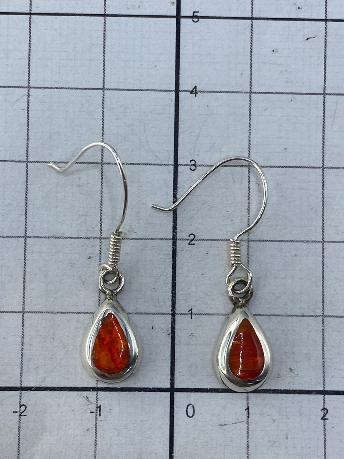 Aretes sobre fondo gris neutro con brillo del ópalo y Quinto 925 visibles