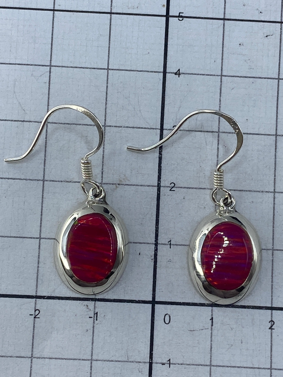 Aretes en la báscula de joyero mostrando 2.58 gramos y el Quinto 925 en el reverso