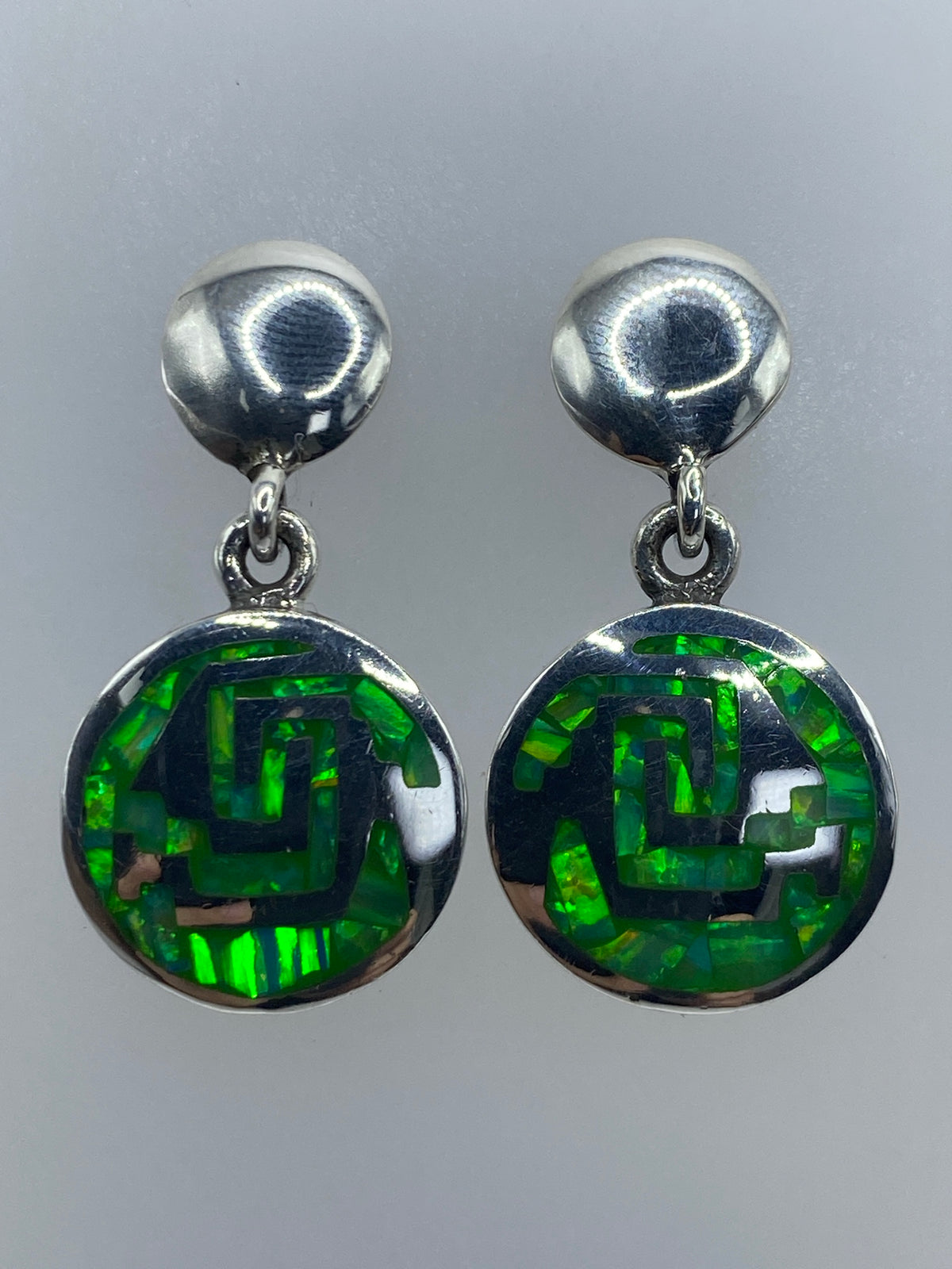 Aretes colocados sobre fondo gris, vista frontal del diseño prehispánico completo
