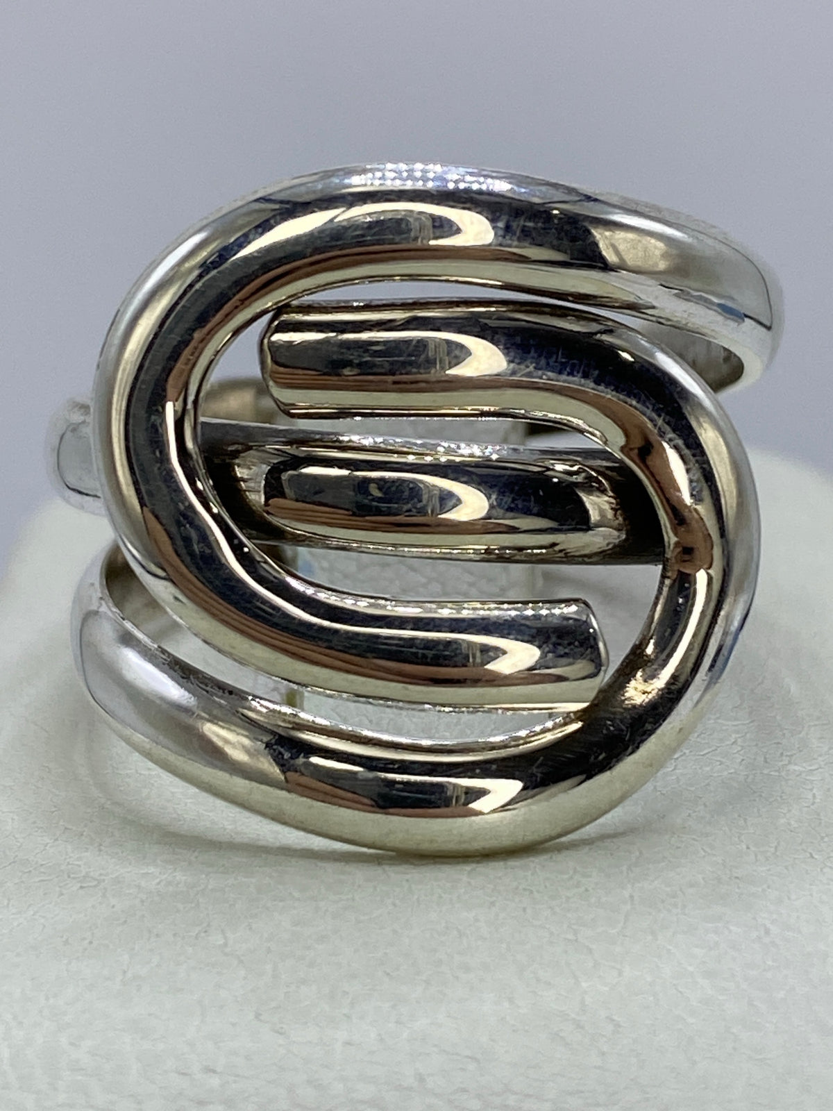 Anillo de plata 925 con calado geométrico de óvalos entrelazados, vista frontal sobre fondo gris