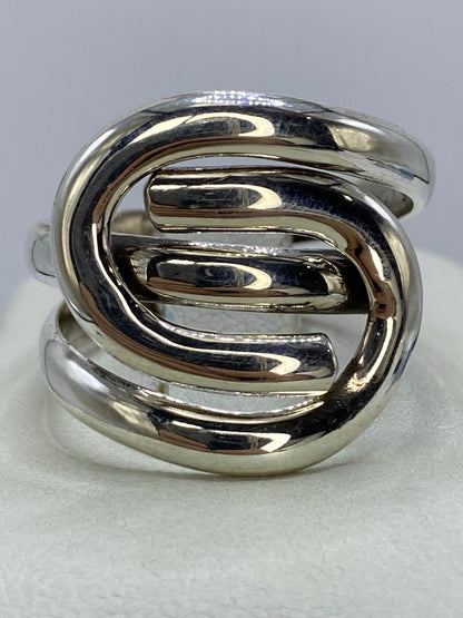 Anillo de plata 925 con calado geométrico de óvalos entrelazados, vista frontal sobre fondo gris