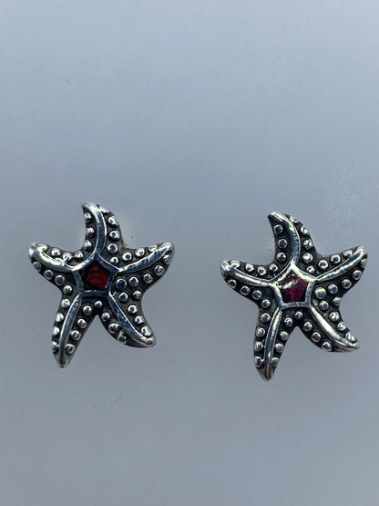 Aretes de tamaño miniatura (1.4 cm) sobre regla de centímetros, con poste y mariposa visible