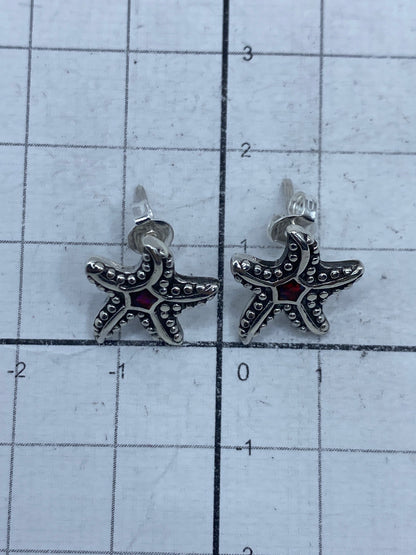 Par de aretes con ópalo de fuego rojo en mano, mostrando el brillo y color del acabado