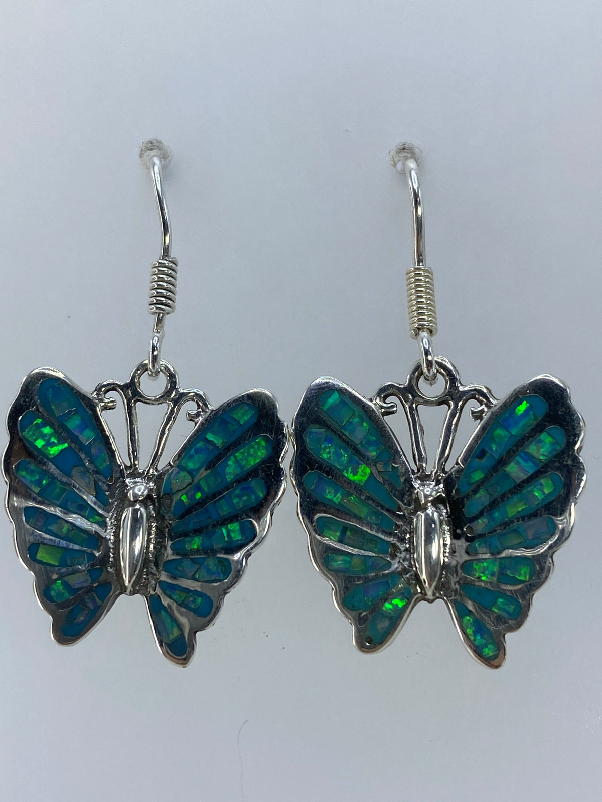Aretes de ópalo viendo el patrón iridiscente verde-azul