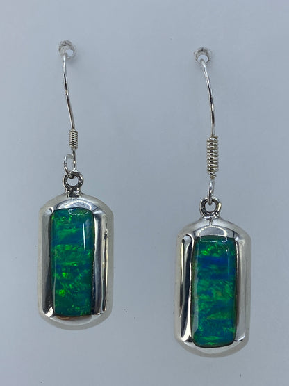 Par de aretes de plata con ópalo de fuego verde limón, puestos en el oído