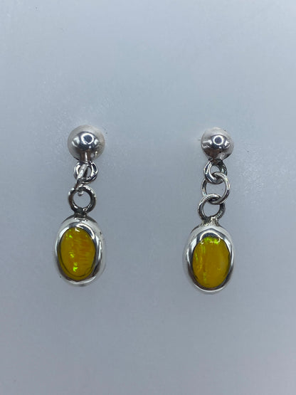 Par de aretes de plata 925 con ópalo de fuego amarillo, colgando sobre fondo gris