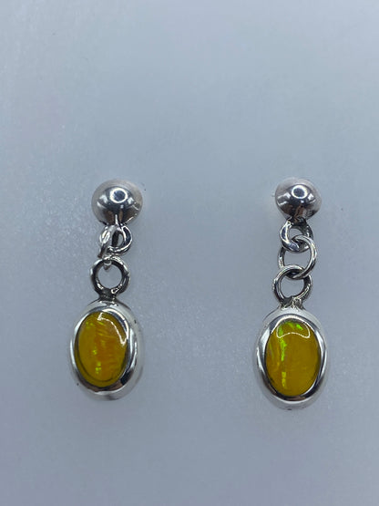Detalle frontal de los aretes mostrando el ópalo de fuego amarillo engastado en plata