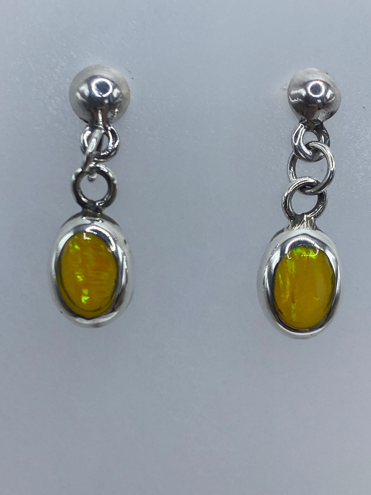 Aretes de ópalo sobre escala de medidas, mostrando tamaño de 2 cm de largo