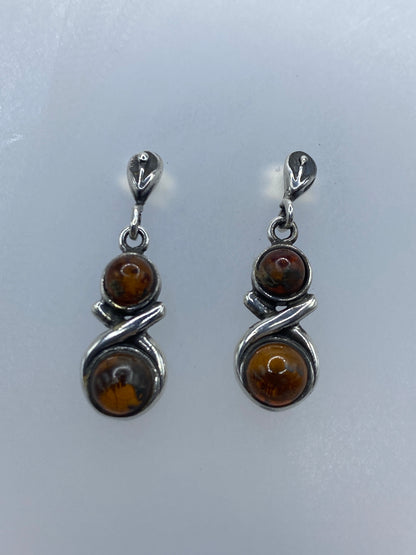 Vista frontal de los aretes con ámbar cálido y plata 925 brillante