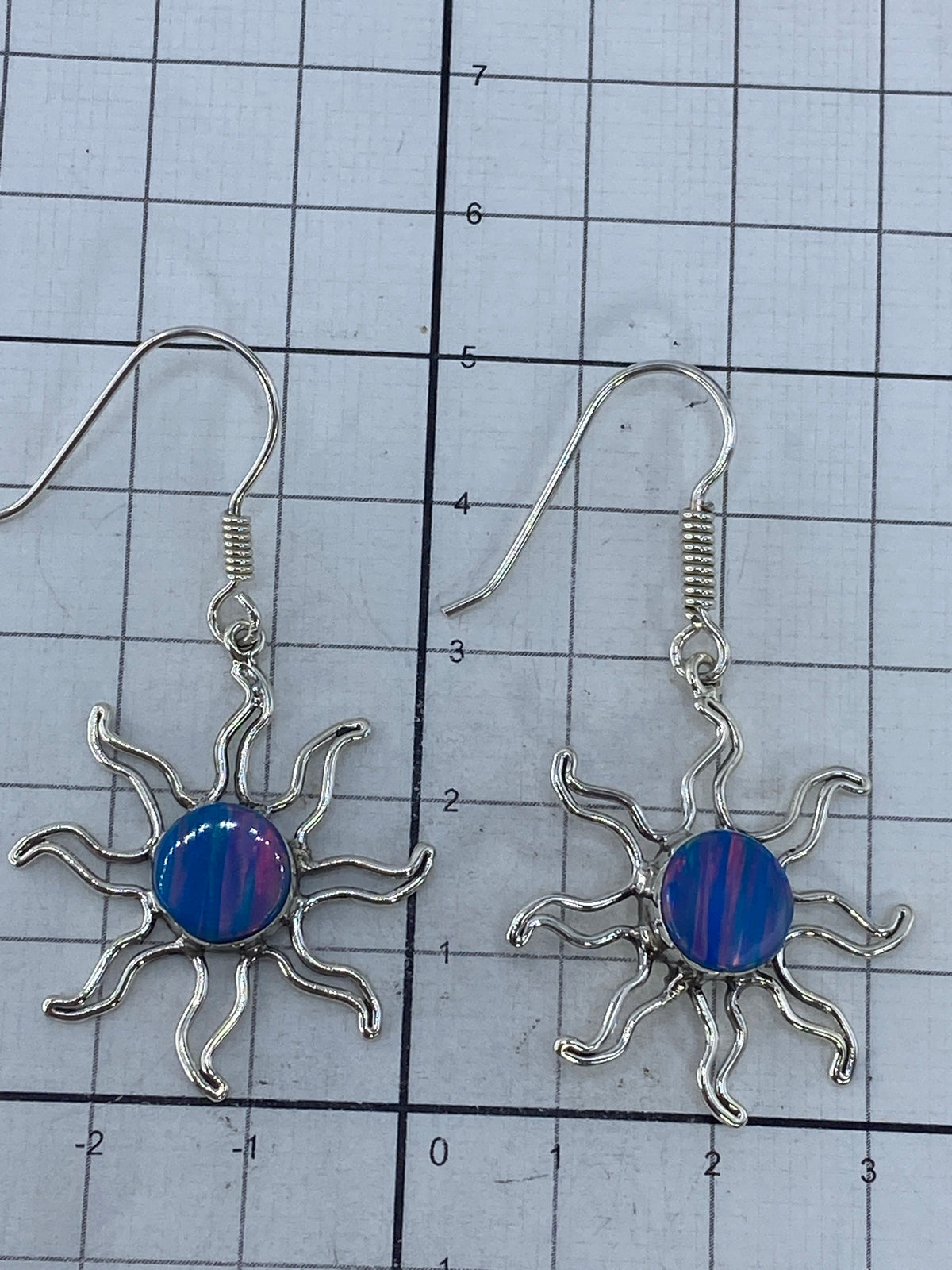 Aretes de ópalo de fuego colocados sobre superficie blanca, midiendo 5 cm de largo del par