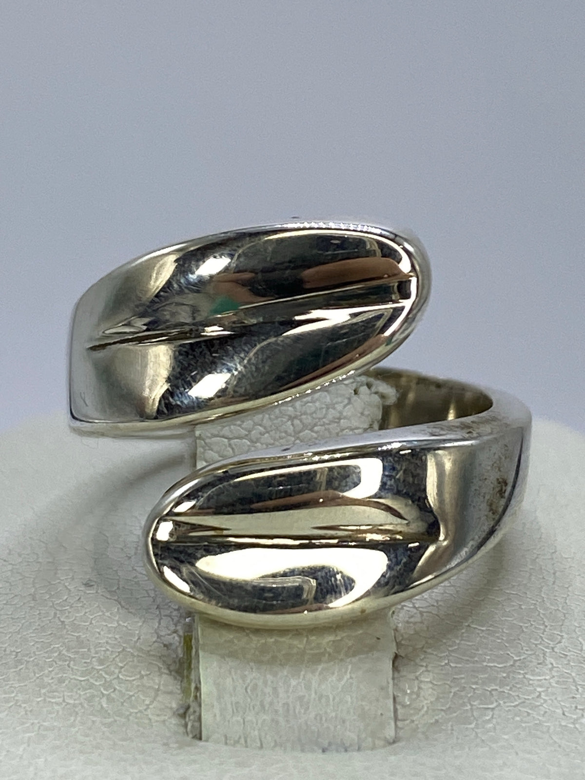 Anillo de plata cartoneado minimalista en la mano de una mujer, vista frontal del volumen 3D