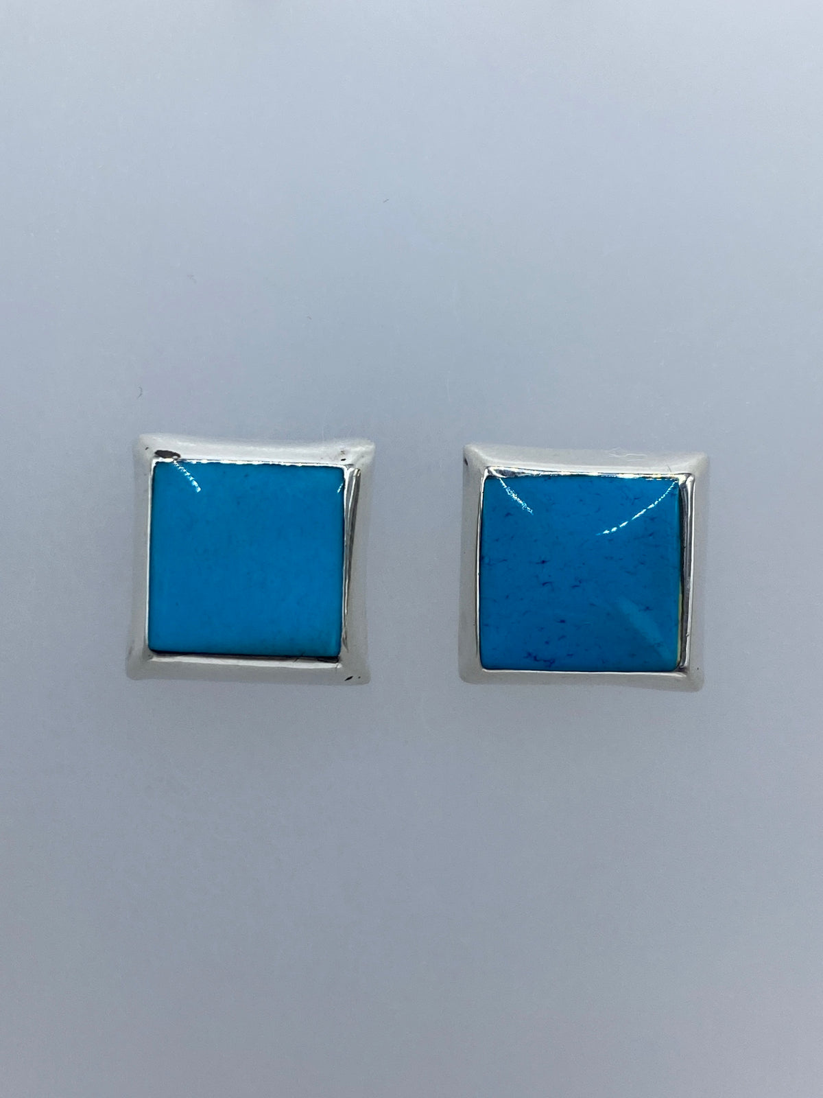Aretes de plata con turquesa azul engastada, vista frontal del par