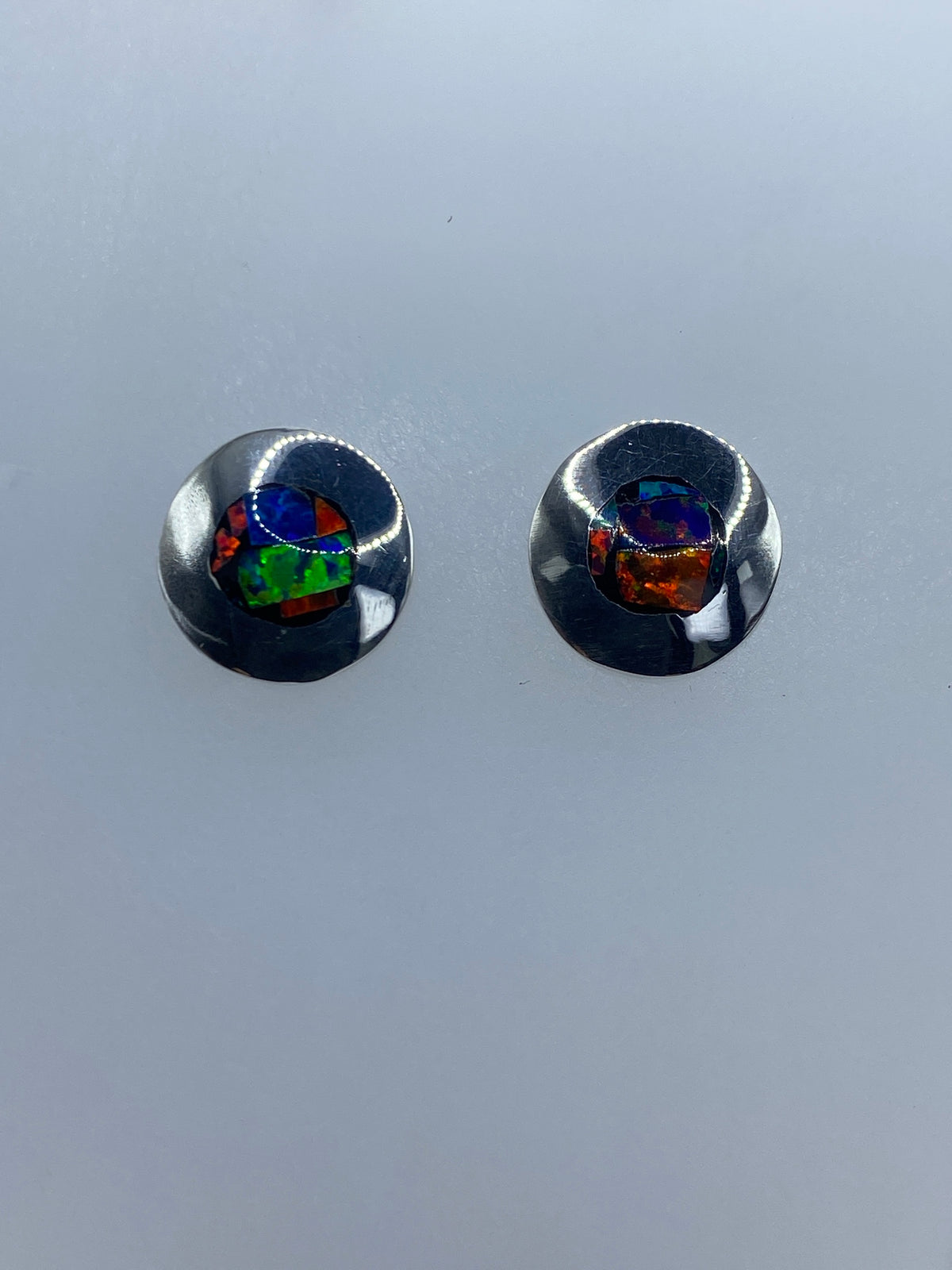 Detalle de aretes de ópalo de fuego mostrando colores azules, verdes y naranjas