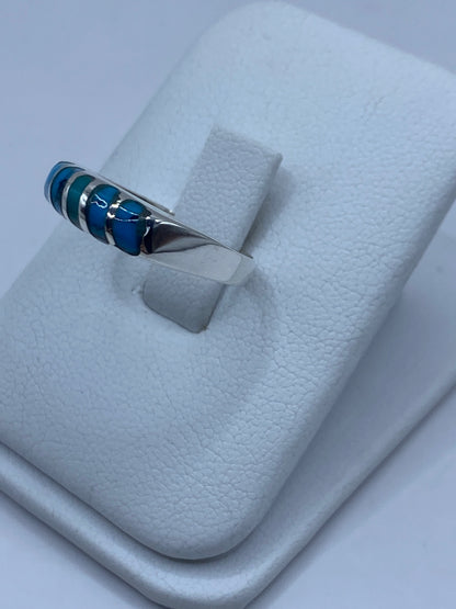 Detalle lateral del anillo mostrando el engaste de turquesas y la plata pulida