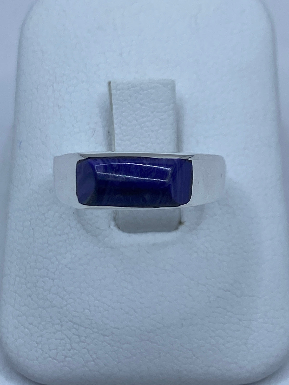 Anillo de plata con piedra morada engastada, vista superior sobre fondo blanco