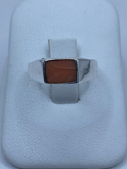 Anillo de plata 925 con coral engastado en la mano de una mujer