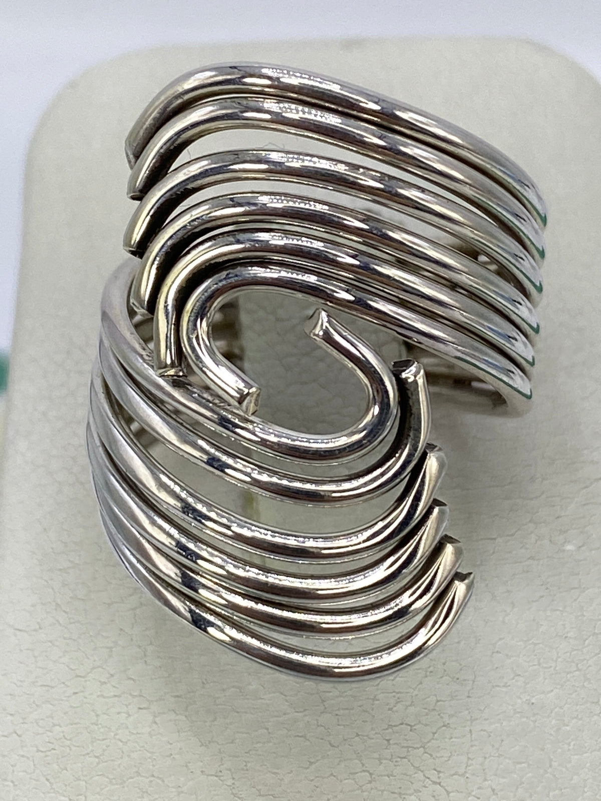 Anillo de plata calado geométrico en la mano de una mujer, mostrando el diseño cortado a mano