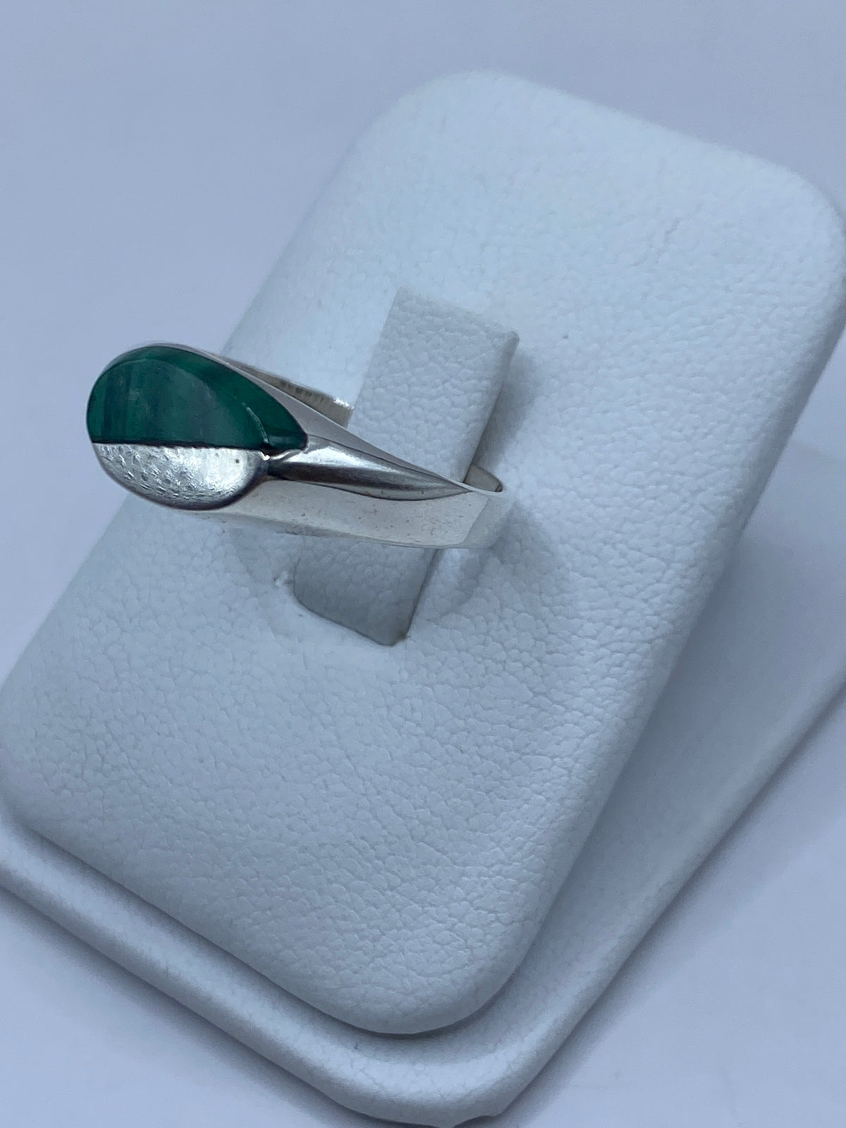Anillo de plata con malaquita en la mano, mostrando el patrón natural de la piedra verde
