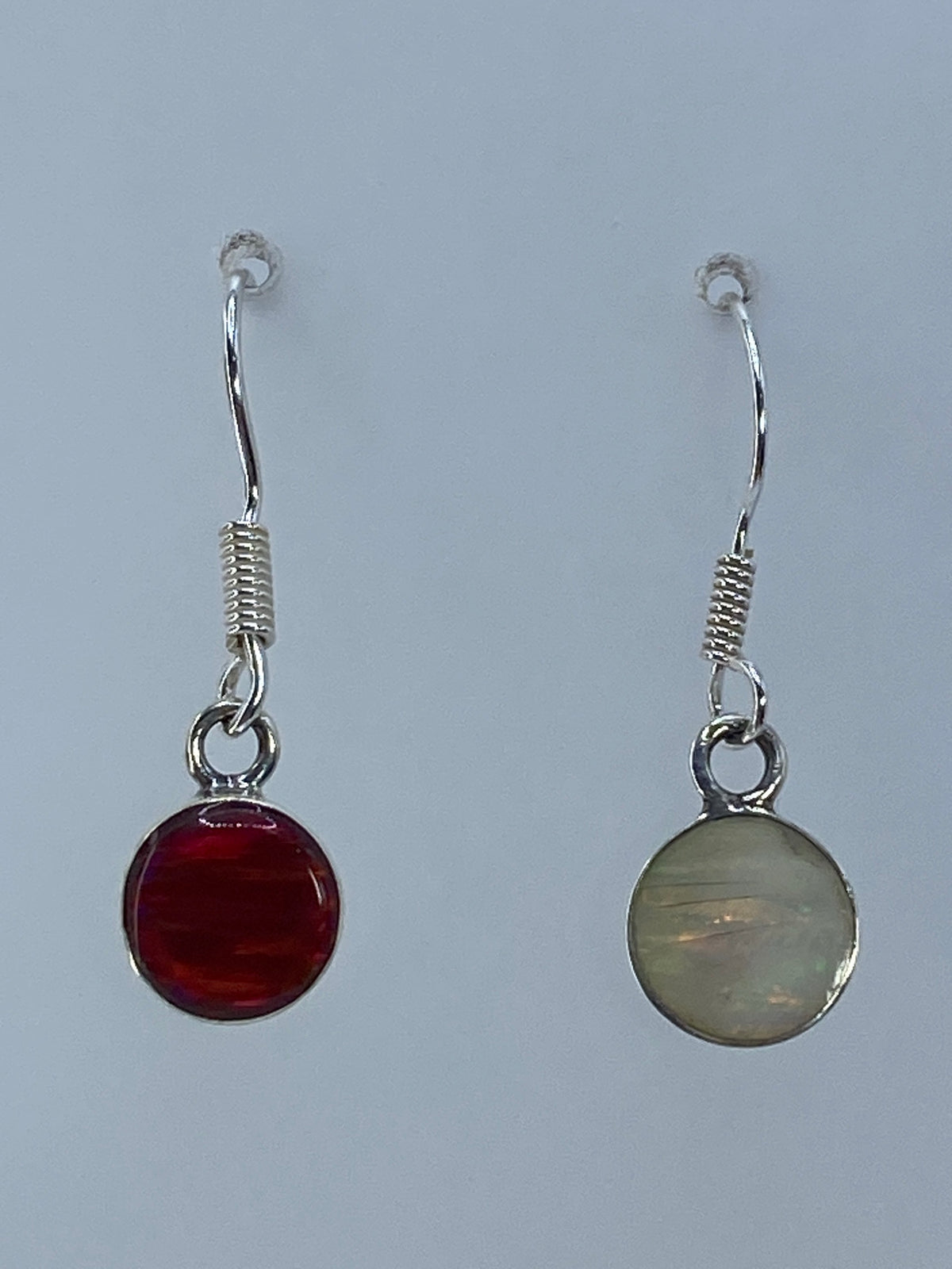 Par de aretes de plata 950 con ópalo de fuego multicolor, mostrando tonos naranja y rojo bajo la luz