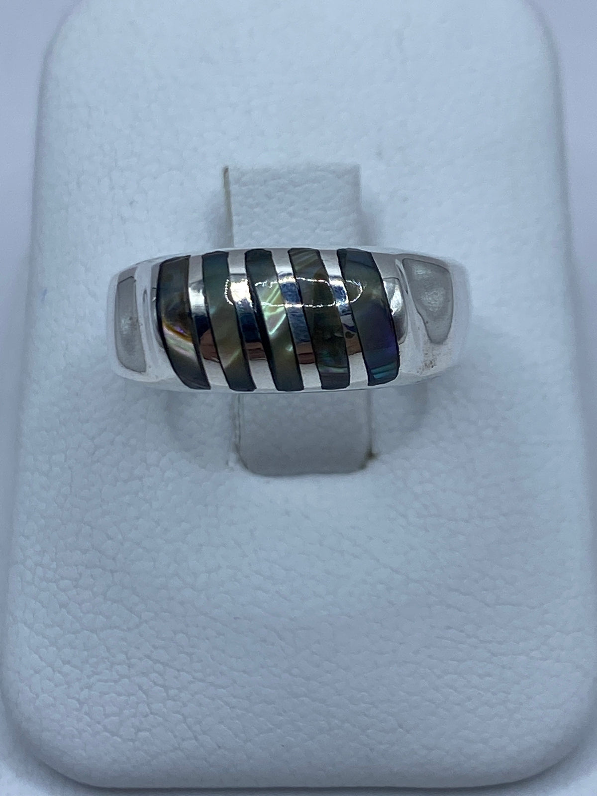 Anillo de plata 925 con concha de abulón iridiscente sobre dedo, tonos azul verdoso y púrpura