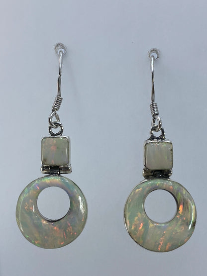 Par de aretes de plata 950 con ópalo de fuego multicolor colgando sobre fondo blanco