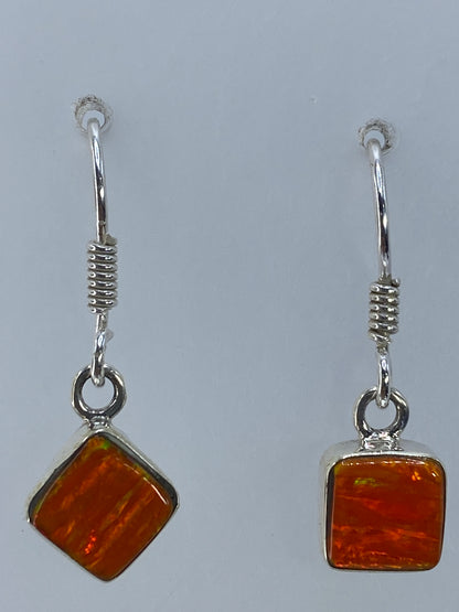 Aretes con ópalo naranja sobre regla mostrando el tamaño de 2.8 cm