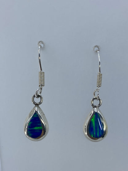 Detalle del ópalo de fuego en los aretes mostrando reflejos verde profundo