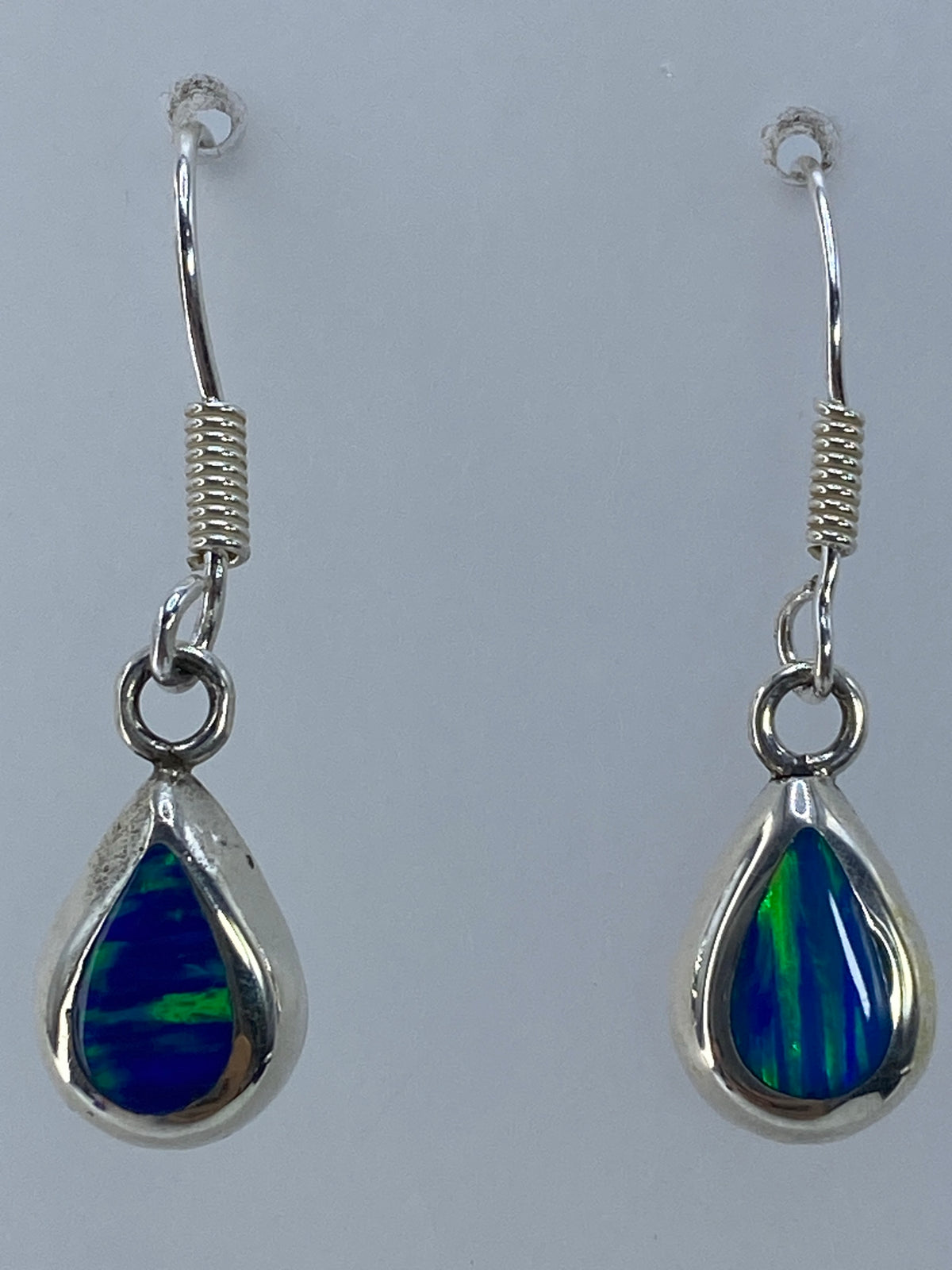 Aretes de plata colgando sobre escala métrica, 3 cm de largo
