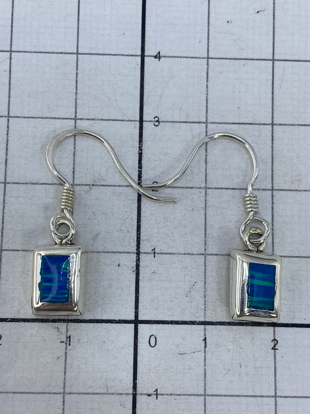Aretes sobre fondo blanco con gancho de plata, vista frontal del Quinto