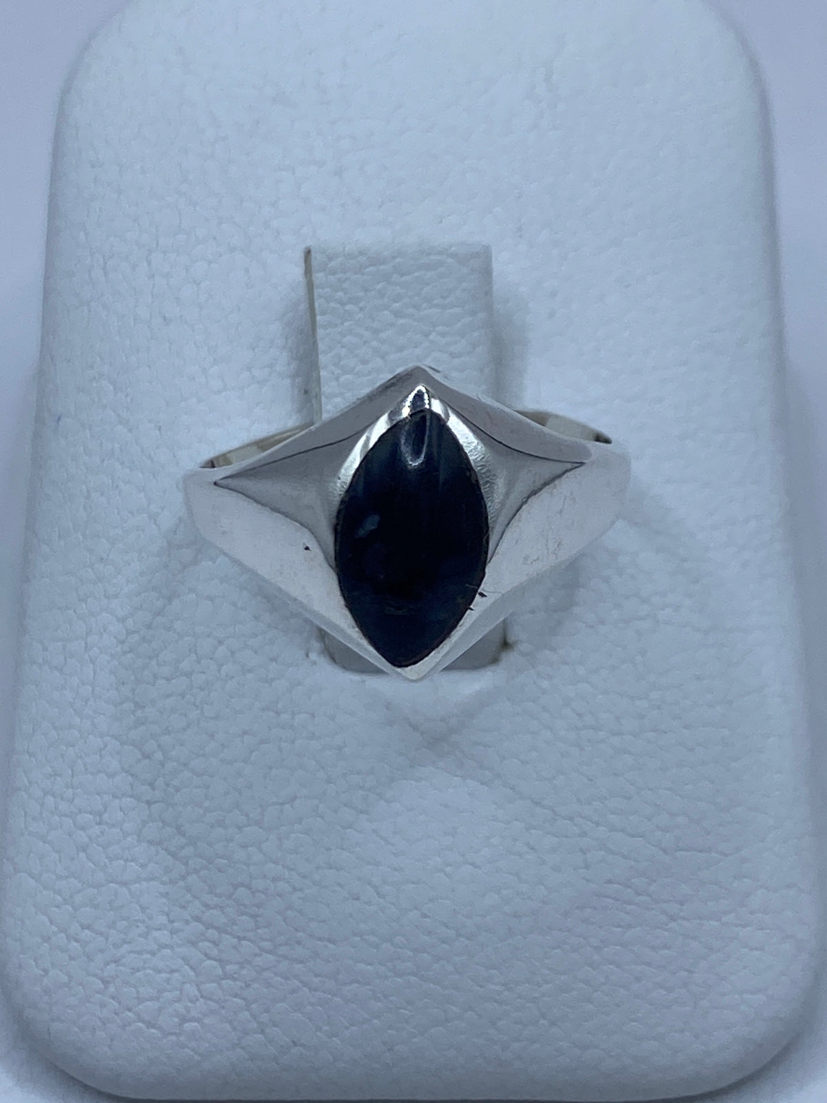 Anillo de plata 925 con piedra engastada a mano, vista frontal sobre almohadilla blanca