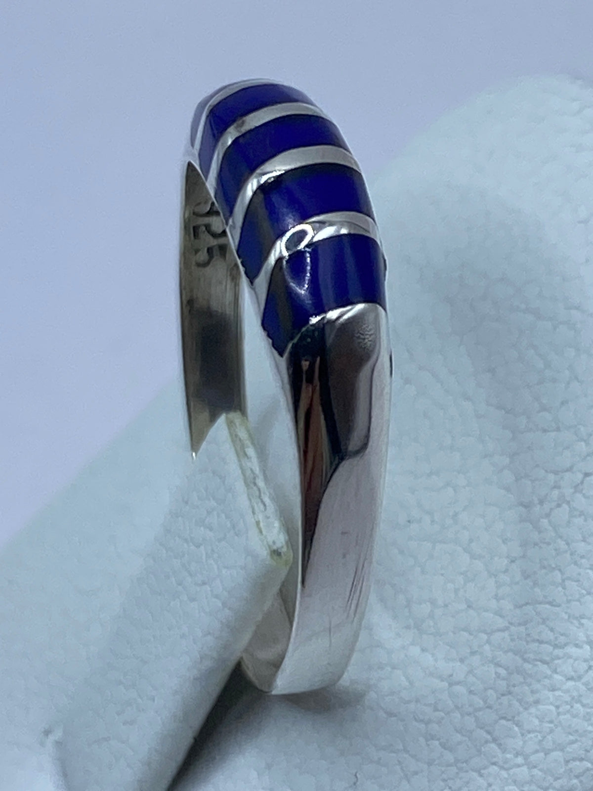 Anillo puesto en el dedo índice, lapislázuli brillante entre plata pulida