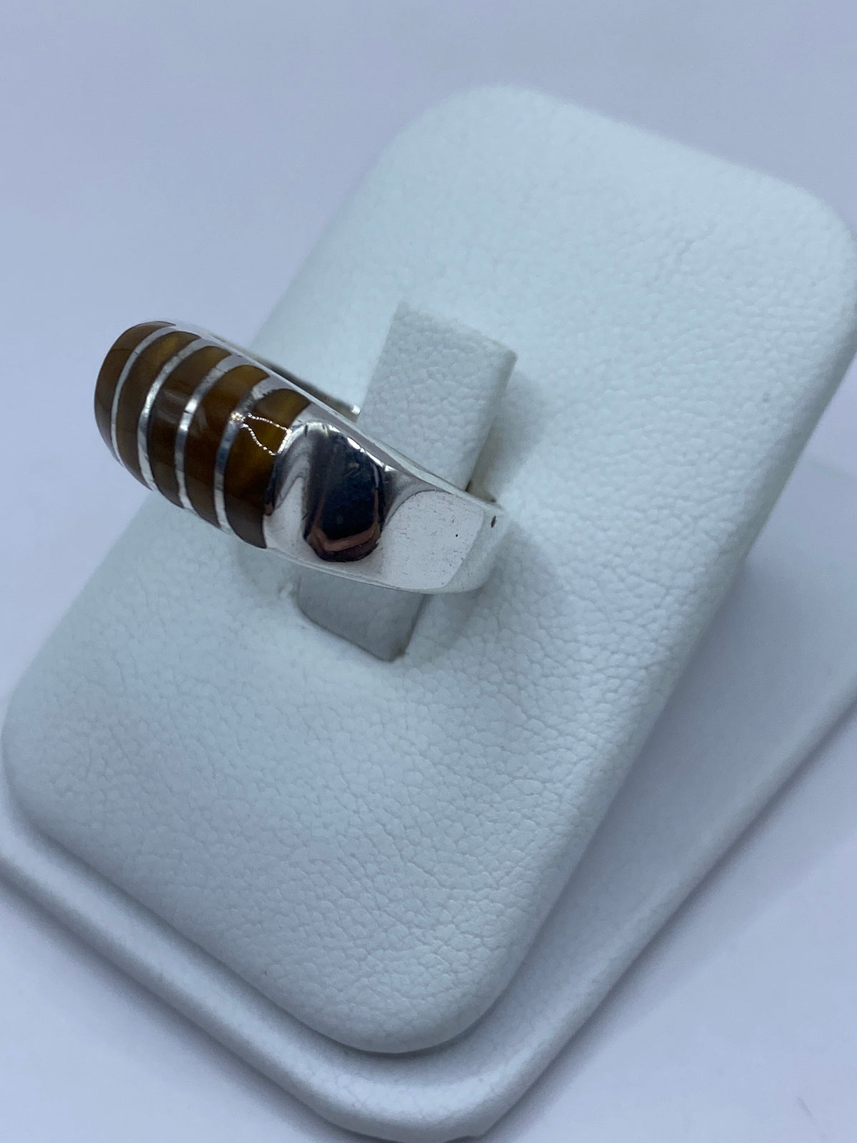 Detalle lateral del anillo mostrando el engaste a mano del Ojo de Tigre y el pulido de la plata