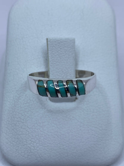Anillo de plata con turquesa azul cielo engastada a mano, en dedos sobre fondo blanco